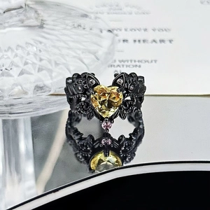 Detailed close-up of gothic heart ring with yellow gemstone and black floral carving