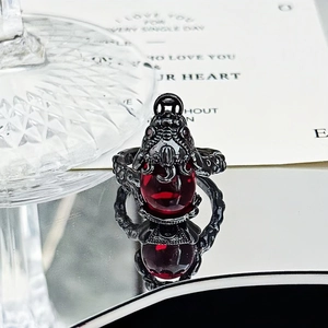 Detail of gothic ring featuring dark metal scales and a large faceted red gemstone