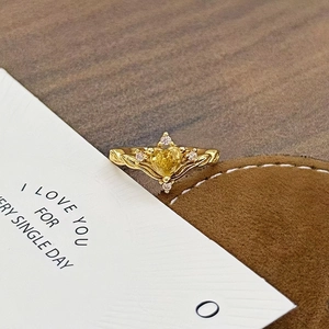 Nahaufnahme des Vintage-Goldrings mit herzförmigem gelbem Edelstein auf Samtbeutel