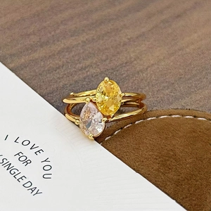 Makroaufnahme Doppelreihiger Goldring mit gelbem Oval-Edelstein und Tropfen-Zirkon