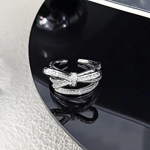 Macro shot of polished silver bow ring with shimmering cubic zirconia on black base