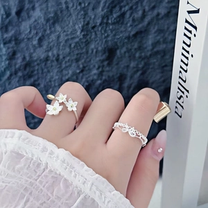 Detail shot of elegant floral open ring and lace silver band against a blue textured backdrop