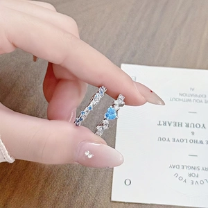 Close-up of a heart-shaped blue zircon ring and a matching silver pavé eternity band