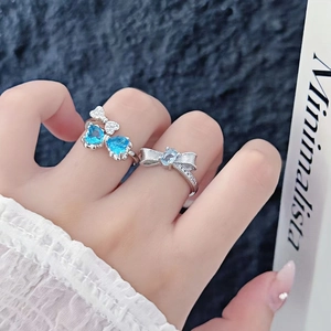 Detail of silver bow rings featuring blue heart gemstones and sparkling zircon accents