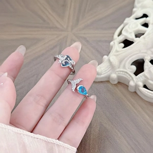 Macro detail of adjustable silver rings with heart-shaped blue zircon and dolphin tail motifs