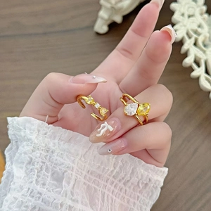 Detail von goldenen Stapelringen mit gelben und weißen Zirkon-Tropfen an der Hand