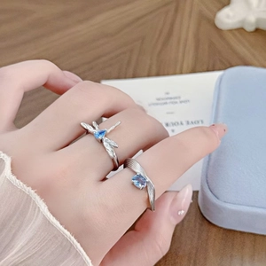 Silver open rings featuring dragonfly design and blue zircon on female hand