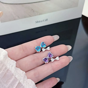 Detail of silver bow rings featuring blue and purple heart stones worn by a model