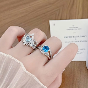Detailed view of luxury silver rings with crown design and heart blue gemstone