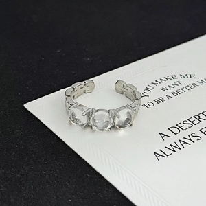 Detail of adjustable silver ring with three clear zircons on a white card background