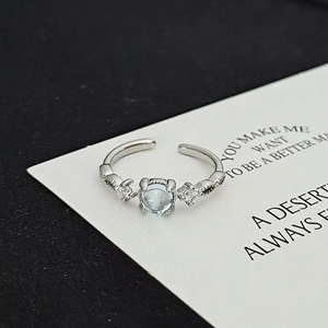 Macro detail of adjustable silver ring featuring a light blue gemstone and zircon inlay