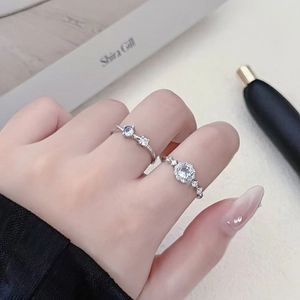 Primer plano de anillos de plata con flores de circón azul y gemas en la mano de modelo