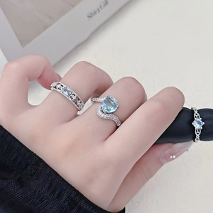 Detalle de tres anillos de plata con circonitas azul claro en forma de corazón y óvalo