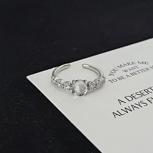 Detail view of moonstone and zircon inlaid silver ring on white display card