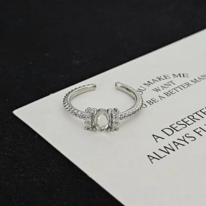 Close-up of silver twist band ring with oval zircon and side stones on aesthetic background