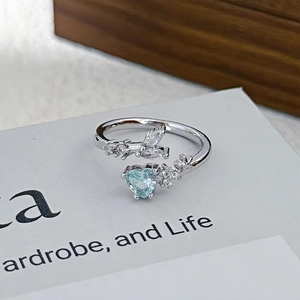 Detalle de circonita azul corazón en un anillo de plata ajustable con diseño floral