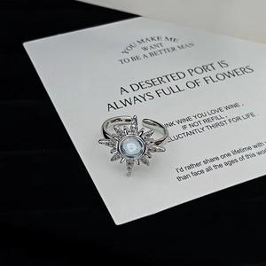 Detailed view of silver sunburst ring with blue gemstone on white card backdrop