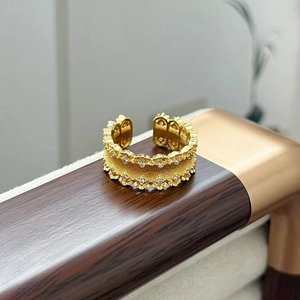 Dettaglio di un anello a fiore vintage in oro spazzolato con zirconi su base in legno
