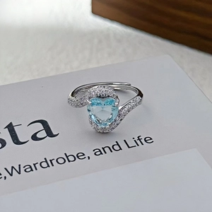 Foto macro de anillo plateado con circón de corazón azul claro y pavé lateral