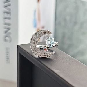 Dettaglio dell'anello a mezzaluna d'argento con pietra azzurra e stella arancione vivace