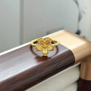 Vista macro dell'anello a fiore in oro spazzolato con stame centrale e fascia a treccia