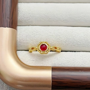 Nahaufnahme eines goldenen Vintage-Rings mit rotem Edelstein und gewebtem Band