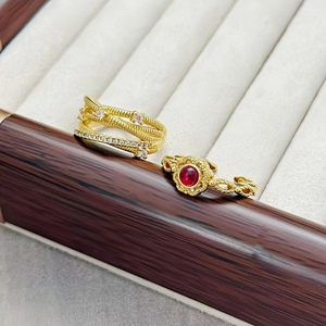 Detailansicht goldener Vintage-Ringe mit weißen Zirkonia und rotem Edelstein auf Samt