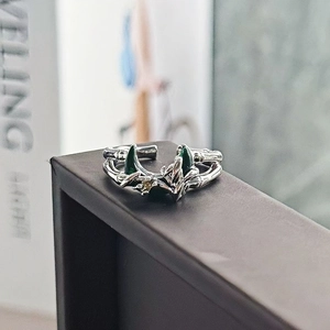 Dettaglio macro di un anello aperto in argento con lune verde scuro e trama in bambù
