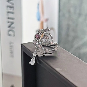 Dettaglio macro di anello luna e cuore in argento con zircone rosa e pendente