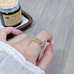 Nahaufnahme eines Vintage-Goldrings mit filigranen Blumen und buntem Emaille-Inlay