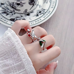 Dettaglio dell'anello a ramo di spine con fiore rosso e pietra verde sul dito modella