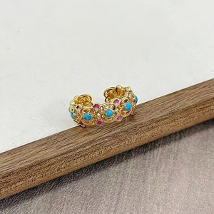 Makro-Detail des Vintage-Emaillerings mit Blumenmuster und Türkis auf Holzgrund