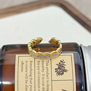 Nahaufnahme eines goldenen Vintage-Rings mit lila und hellblauen Emaille-Blumendetails