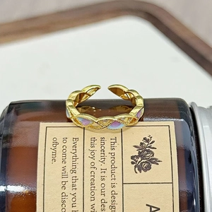 Makroaufnahme eines vergoldeten Rings mit Flechtstruktur und lila-blauer Emaillierung