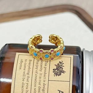Nahaufnahme eines Vintage-Goldrings mit Türkis und lila Emaille auf einer braunen Flasche