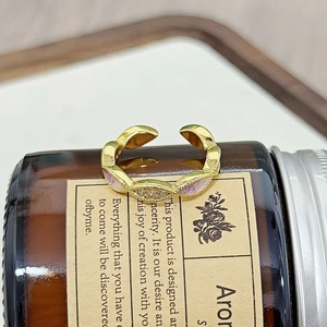 Detailaufnahme eines gewellten Goldrings mit lila Emaille und funkelnden Zirkonia-Steinen