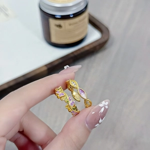Detailaufnahme von Vintage-Emaillering und gewelltem, vergoldetem Ring mit lila Kristallen