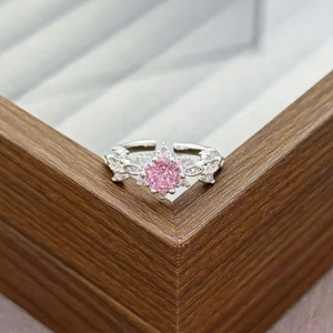 Close-up of pink zircon ring with snowflake design and micro-paved stones on wood box