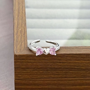 Macro detail of adjustable silver ring featuring pink heart-shaped stones in a bow design