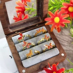 Detailed close-up of vintage butterfly and flower rings with orange zircons in a jewelry box