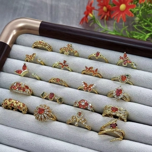 Vintage gold rings set with orange-red zircon stones and floral designs in a display box