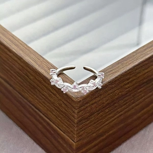 Close-up of adjustable silver ring with pink zircon stones on a wooden jewelry box
