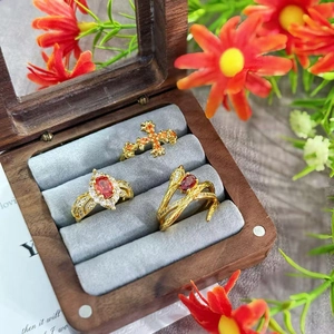 Vintage style gold ring set with red zircon and cross design in a wooden jewelry box