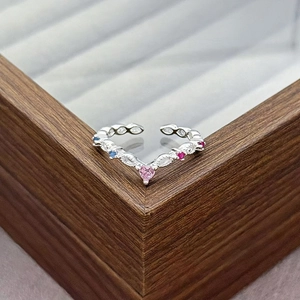 Close-up of V-shaped adjustable silver ring with pink heart stone and colorful gems