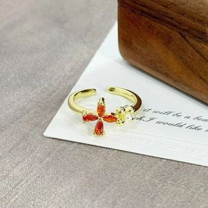 Detailed close-up of vintage gold ring with orange zircons and small pearl flower