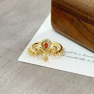 Macro detail of crown ring with orange drop gemstone and intricate golden filigree