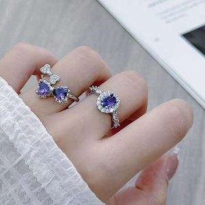 Detail of silver rings with purple heart and oval zircon stones worn by a model