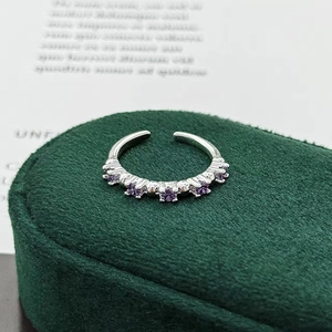 Macro shot of silver open ring with five purple round-cut zircons on green velvet