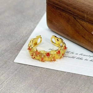 Macro shot of vintage gold open ring featuring red zircon stones and woven texture detail