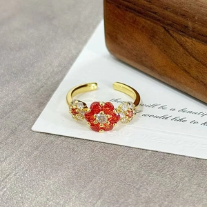 Close-up of vintage flower ring with red gemstone and white crystals on golden open band